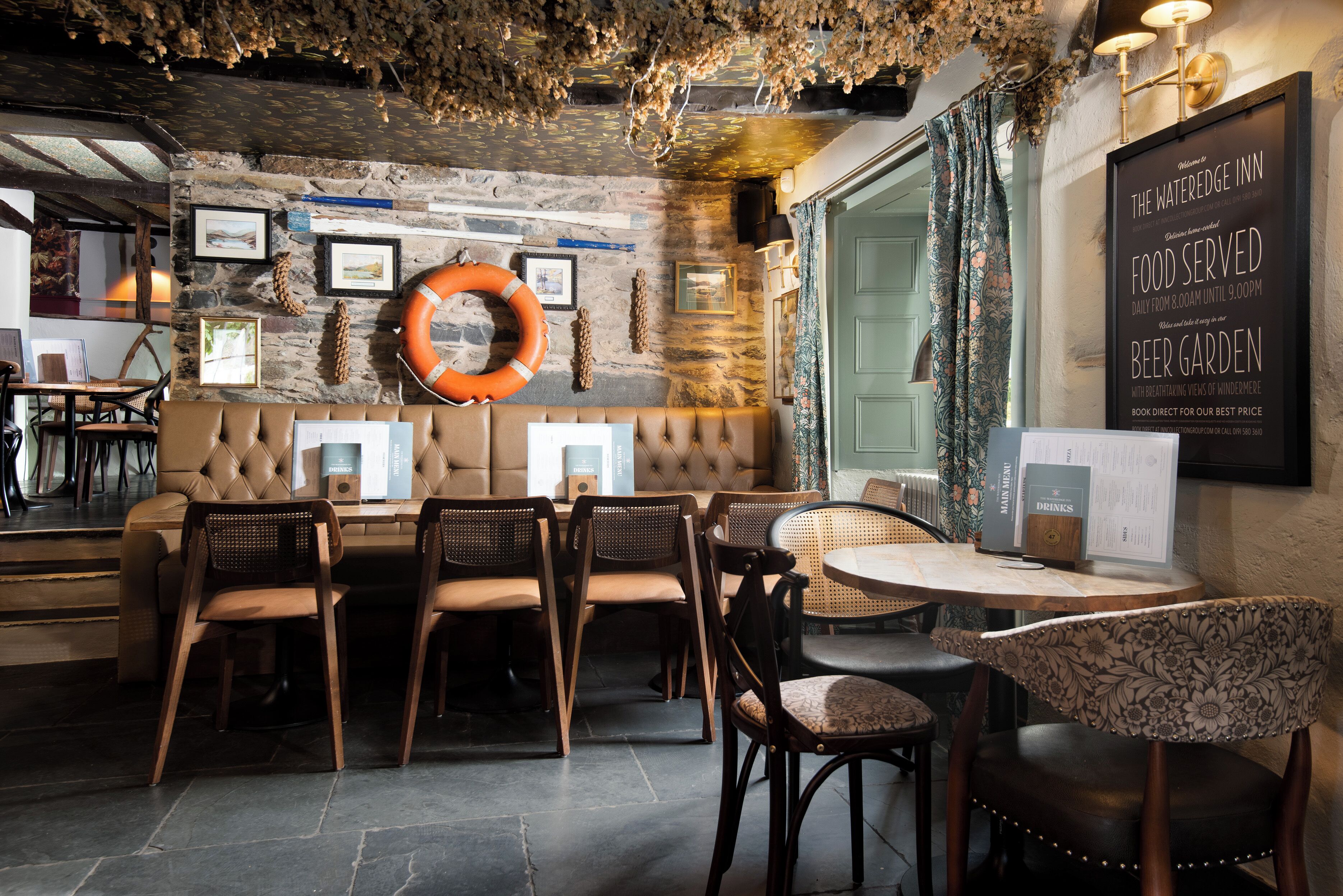 A cozy restaurant with a stone wall, wooden furniture, and a menu board advertising a beer garden.