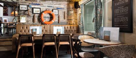 A cozy restaurant with a stone wall, wooden furniture, and a menu board advertising a beer garden.