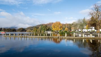 A calm lake with a dock, surrounded by autumn-colored trees and a mountain in the background.