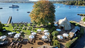 A lakeside restaurant with outdoor seating and a view of boats on the water.
