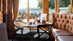 A cozy seating area with a view of a lake and boats, featuring a table with a menu and a chair.