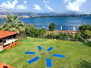 A backyard with a circular play area, a wooden deck, and a view of a lake and mountains.