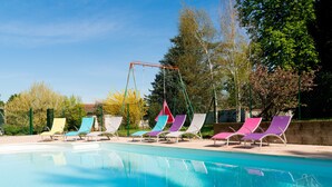 Una piscina con múltiples sillas de descanso y un conjunto de columpios.