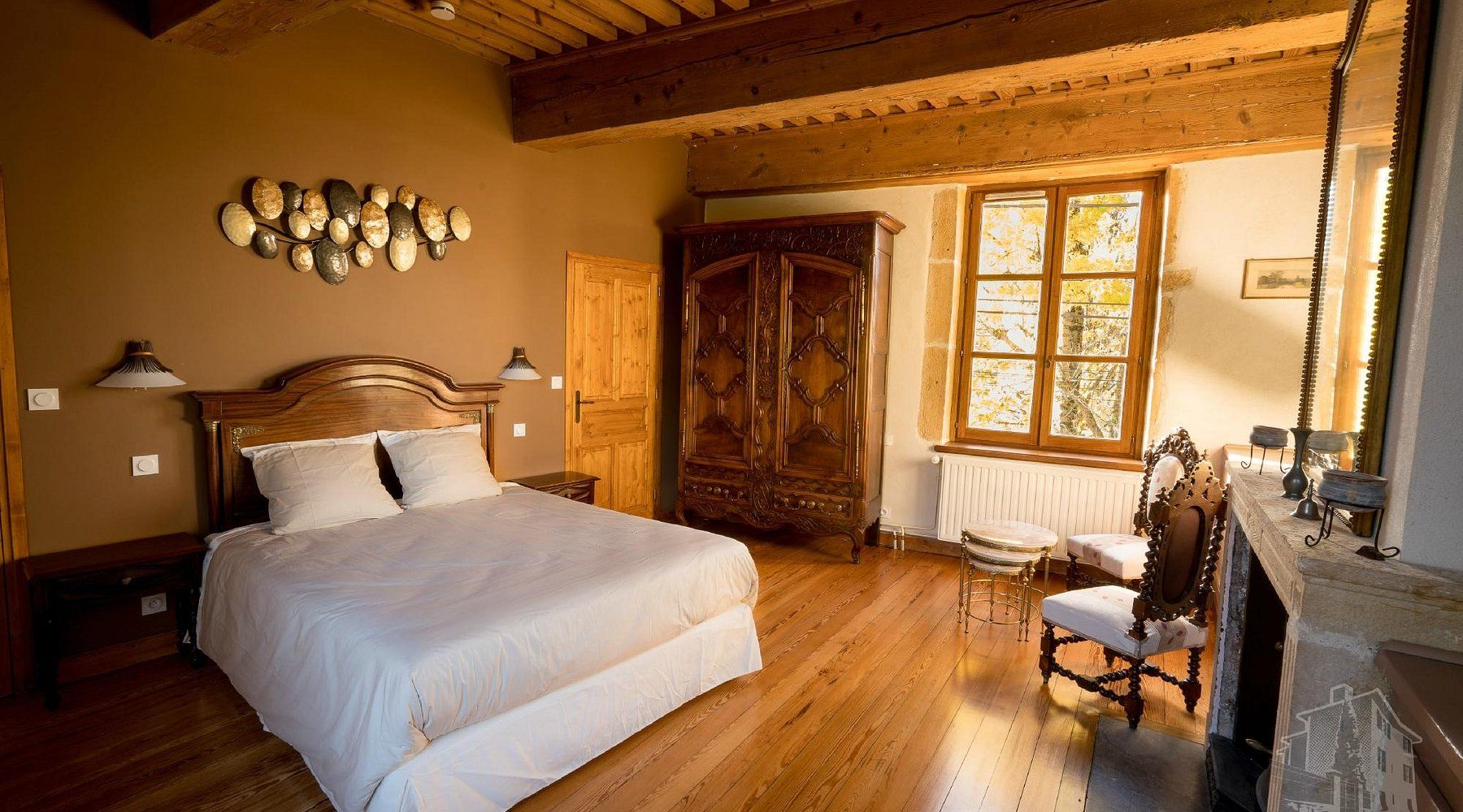 A bedroom with a large bed, wooden wardrobe, and a window with a view.
