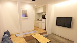 A compact living space with a kitchenette, a flat-screen TV, and a small dining area. - SEKAI HOTEL Momiji (Osaka)