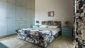 Un dormitorio con cama, mesita de noche, armario y un cuadro en la pared.