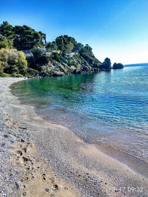 Ein Kiesstrand mit klarem Wasser und steilen Felsküsten.