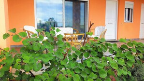Una habitación con un ventanal grande, mobiliario de mimbre y vista a un edificio.