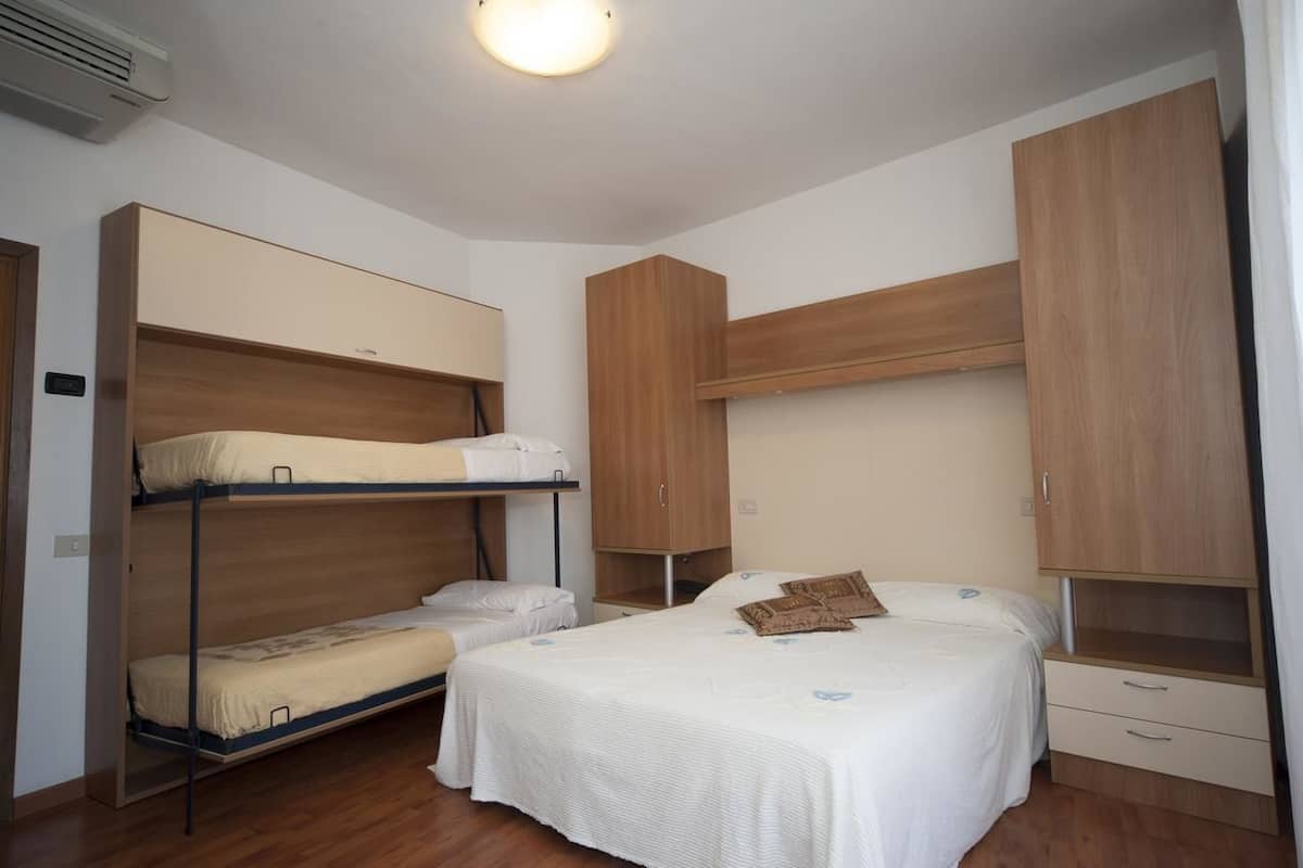 Una habitación con literas, una cama individual y armarios empotrados de madera.