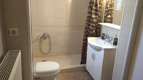 Ein Badezimmer mit Dusche, Toilette, Waschbecken und Spiegel.