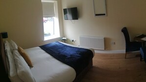 A bedroom with a bed, a chair, a TV, and a window. - Tara View Apartments (Rathfeigh)