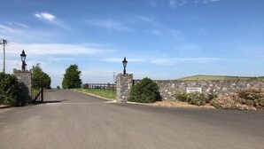 A paved road leading to a stone wall with a sign reading "PUDDENHILL Est. 1981". - Tara View Apartments (Rathfeigh)