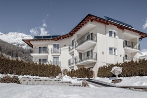 A multi-story hotel with balconies, solar panels, and a mountainous backdrop. - Residenz Allegra (Soelden)