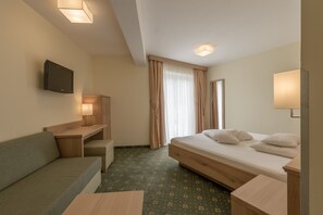 A hotel room with a bed, a sofa, a desk, a TV, and a window with curtains. - Residenz Allegra (Soelden)