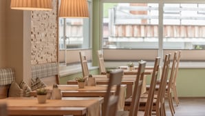 A restaurant interior with wooden tables and chairs, a brick wall, and hanging lamps. - Residenz Allegra (Soelden)