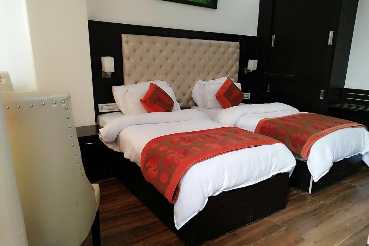 A double bed with a tufted headboard, two pillows, and a red accent pillow.