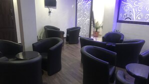 A room with several black cushioned chairs and a small round table. - Hotel Triund Heights (Dharamshala)