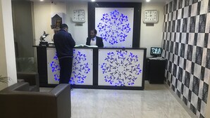 A reception area with a modern design, featuring a reception desk, a chandelier, clocks, and patterned walls. - Hotel Triund Heights (Dharamshala)