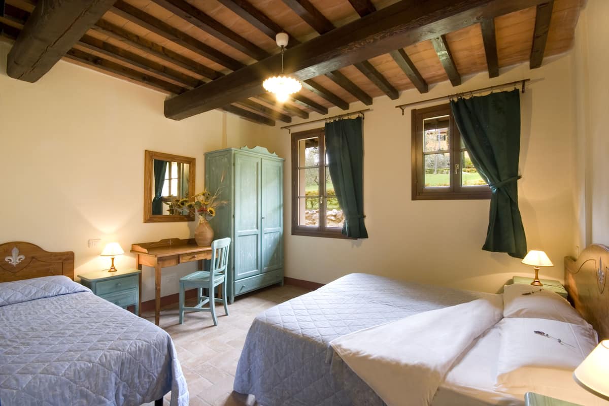 A bedroom with two beds, a desk, a chair, and a wardrobe.