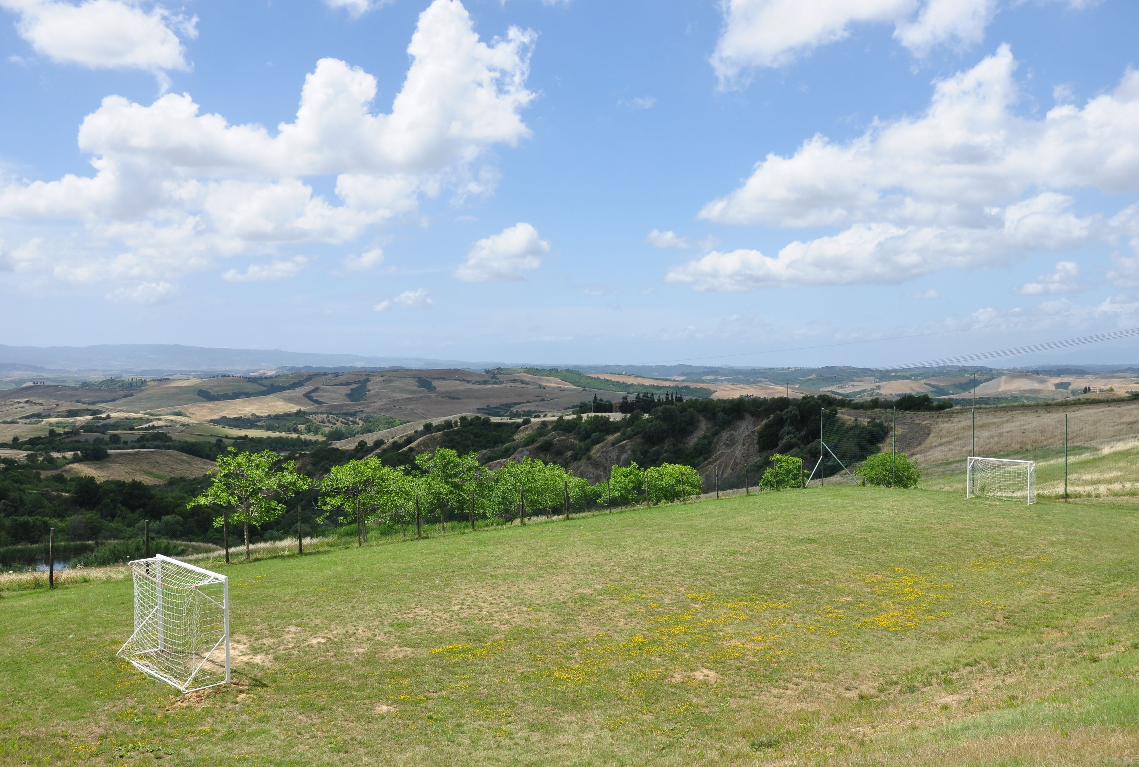 A soccer field with goalposts and a hilly landscape in the background.