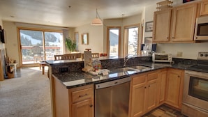A modern kitchen with wooden cabinets, a granite countertop, and stainless steel appliances. - Cinnamon Ridge B304 by SummitCove Vacation Lodging (Keystone)
