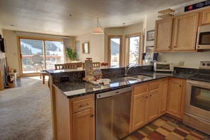 A modern kitchen with wooden cabinets, a granite countertop, and stainless steel appliances. - Cinnamon Ridge B304 by SummitCove Vacation Lodging (Keystone)
