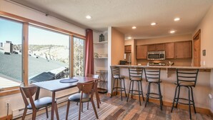 A modern kitchen with a large island, bar stools, and a dining table with chairs. - Montezuma 1771 by SummitCove Vacation Lodging (Keystone)