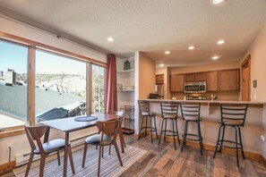 A modern kitchen with a large island, bar stools, and a dining area with a table and chairs.