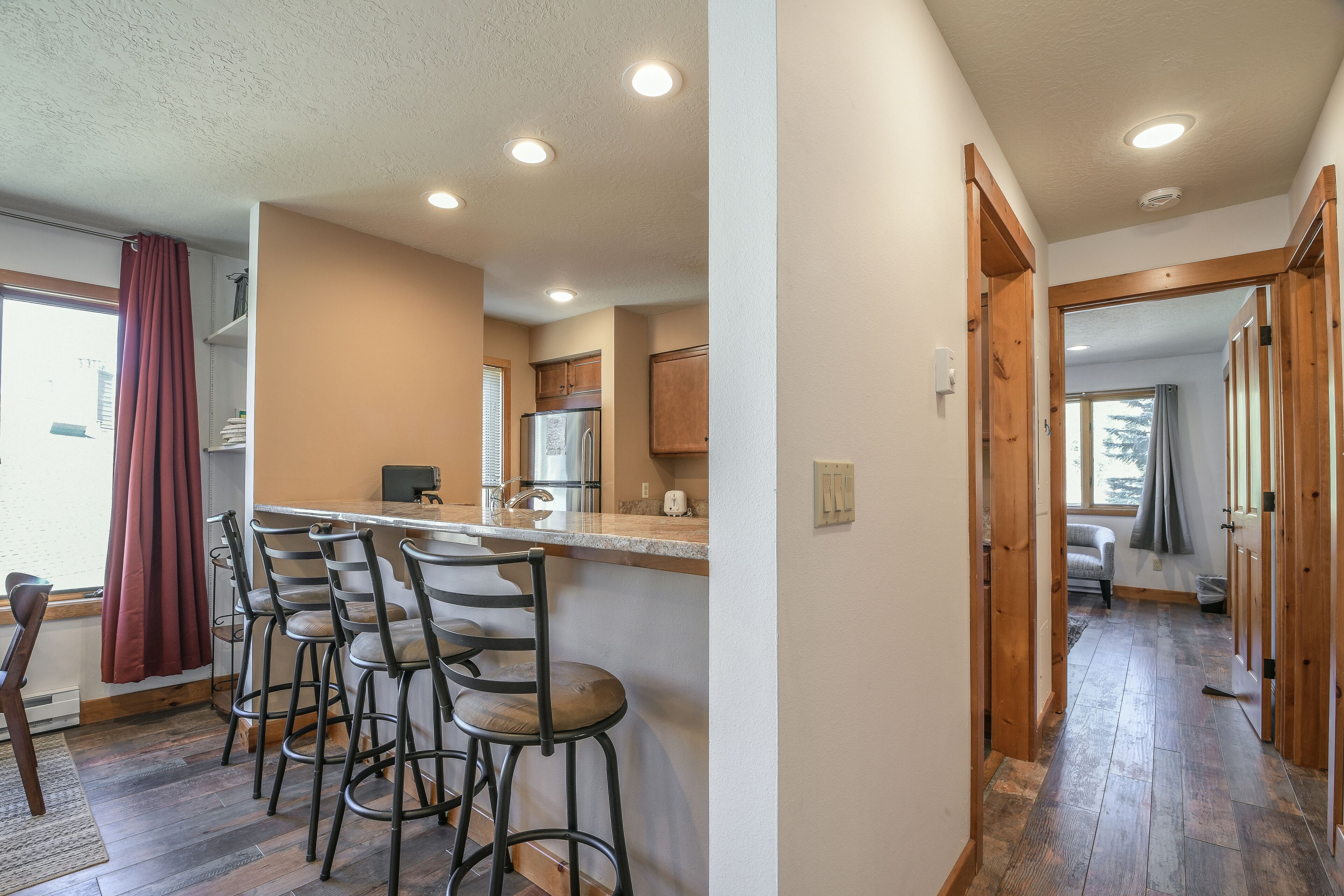 Una cocina con barra, piso de madera y vistas a un dormitorio.