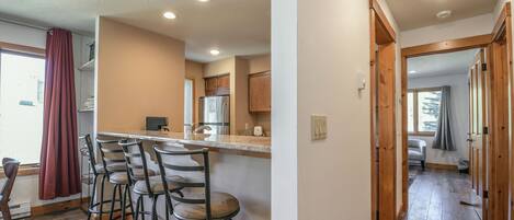 Una cocina con barra, piso de madera y vistas a un dormitorio.