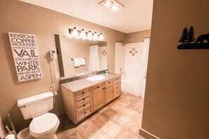 A bathroom with a vanity, toilet, and shower.