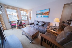 A living room with a sofa, chairs, a coffee table, and a painting on the wall.