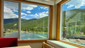 Une pièce dotée d’une grande fenêtre donnant sur un lac et des montagnes boisées.