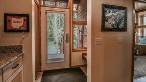 Un intérieur en bois avec une grande porte vitrée donnant sur l’extérieur, une carte encadrée accrochée au mur et un tableau.