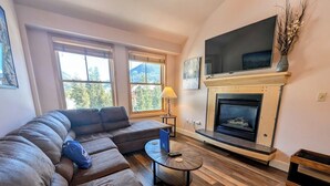 A living room with a sectional sofa, a fireplace, and a TV mounted above it. - Silver Mill 8304 (Keystone)