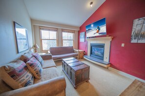 A living room with a red wall, a fireplace, a sofa, and a coffee table. - Silver Mill 8304 (Keystone)
