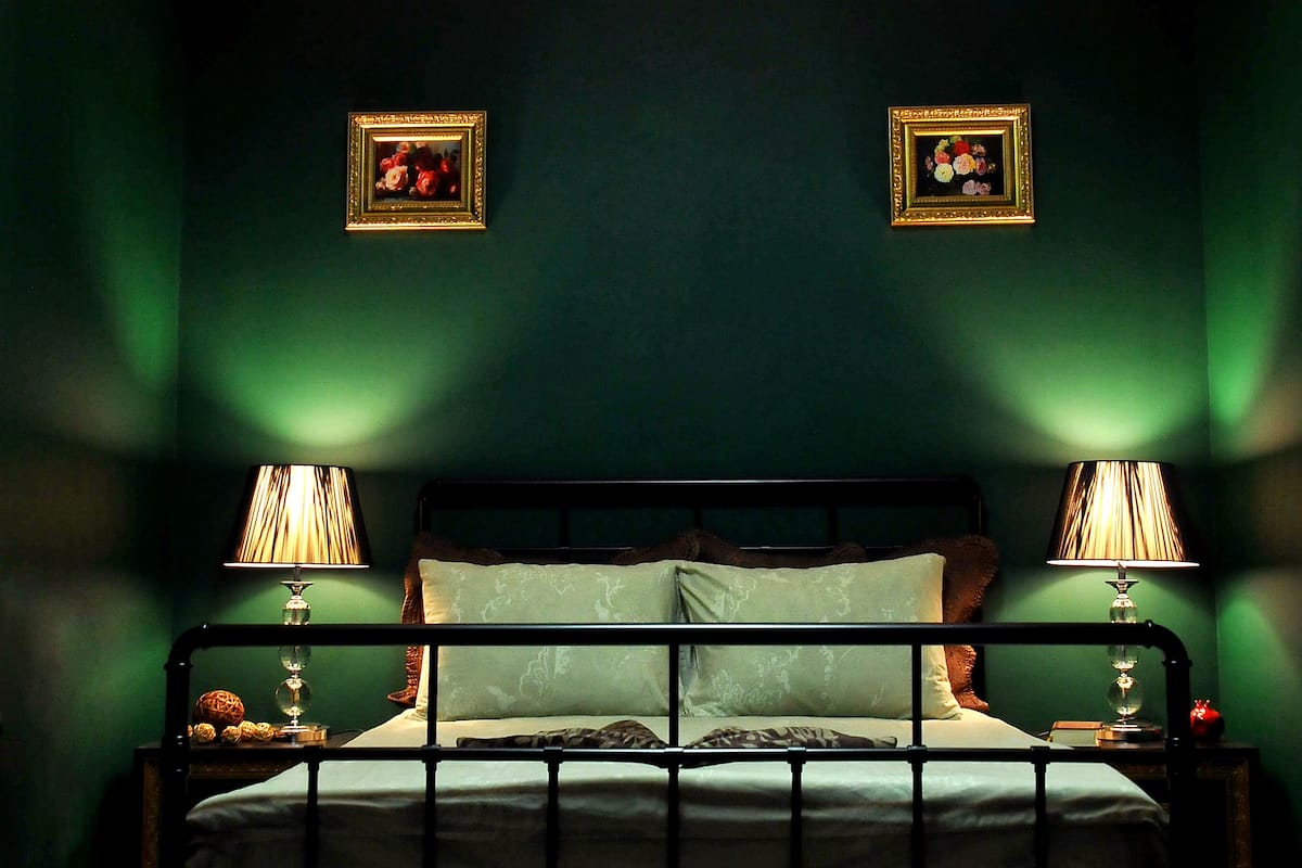 Un lit avec un cadre en métal, deux tables de chevet avec des lampes et deux tableaux encadrés accrochés au mur.