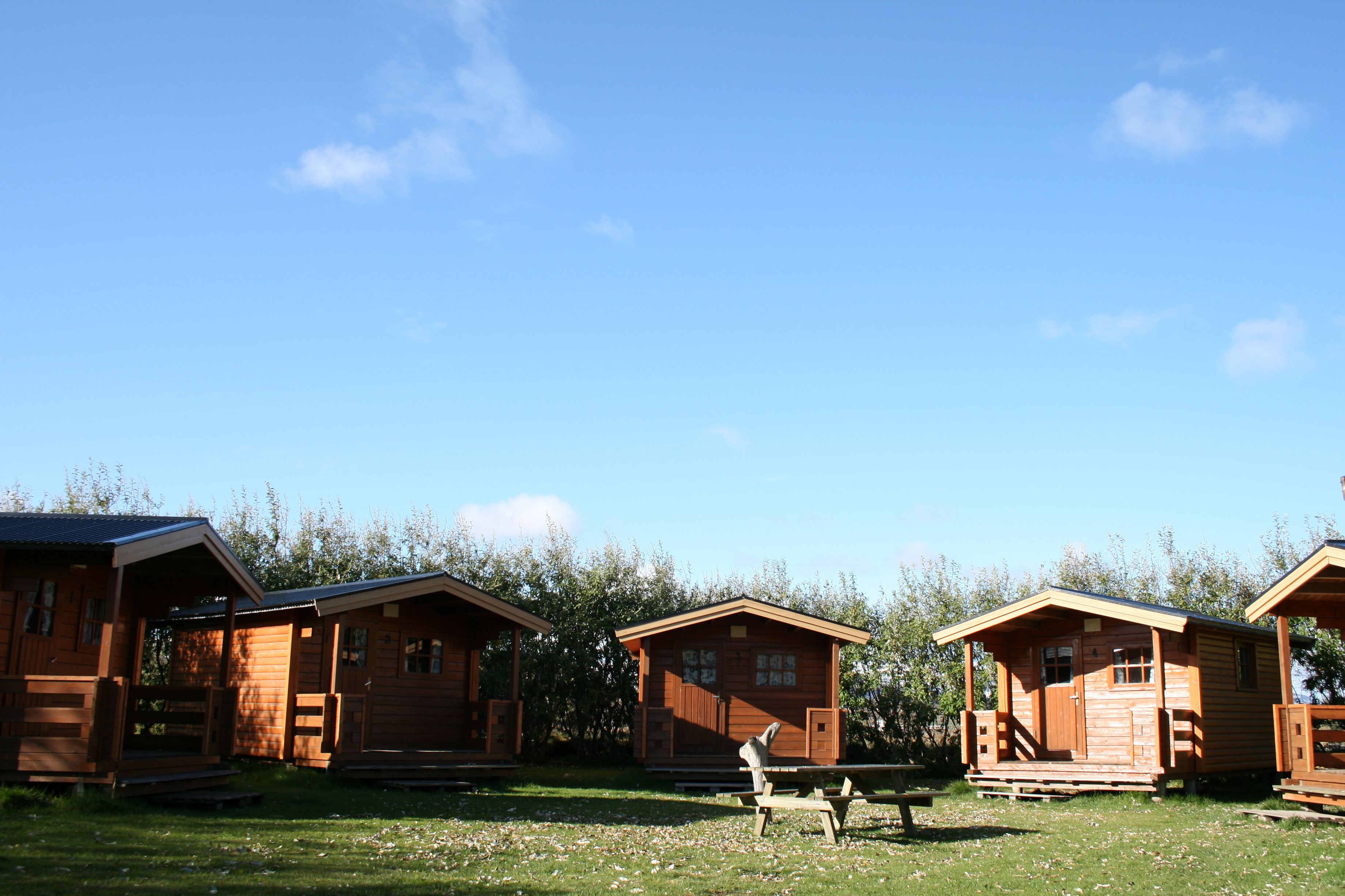 Tres cabañas de madera con un porche y una mesa de picnic al frente.