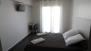 Habitación de hotel con cama, dos almohadas, televisor montado en la pared, escritorio y una silla.