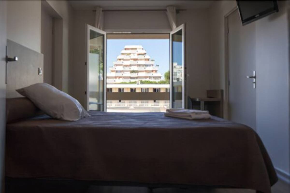 Un dormitorio con cama, almohada y vista a un edificio a través de una puerta abierta.