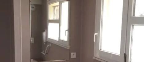 A bathroom with a sink, mirror, window, and a trash bin.