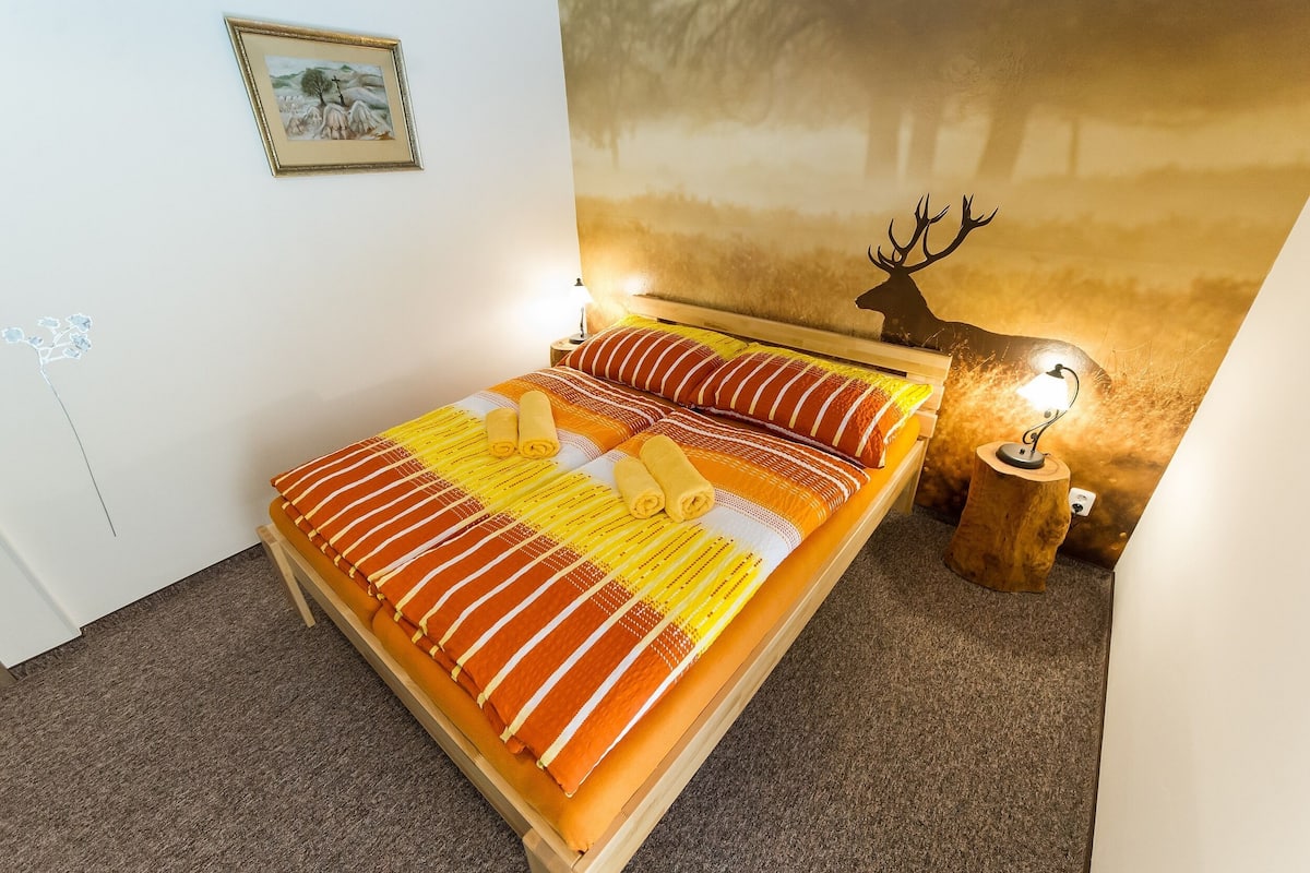 A bed with striped bedding, a wooden headboard, and a wall-mounted deer head decoration.