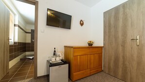 A compact hotel room with a kitchenette, a flat-screen TV, a wooden cabinet, and a large wardrobe. - Penzion Top (Cesky Krumlov)