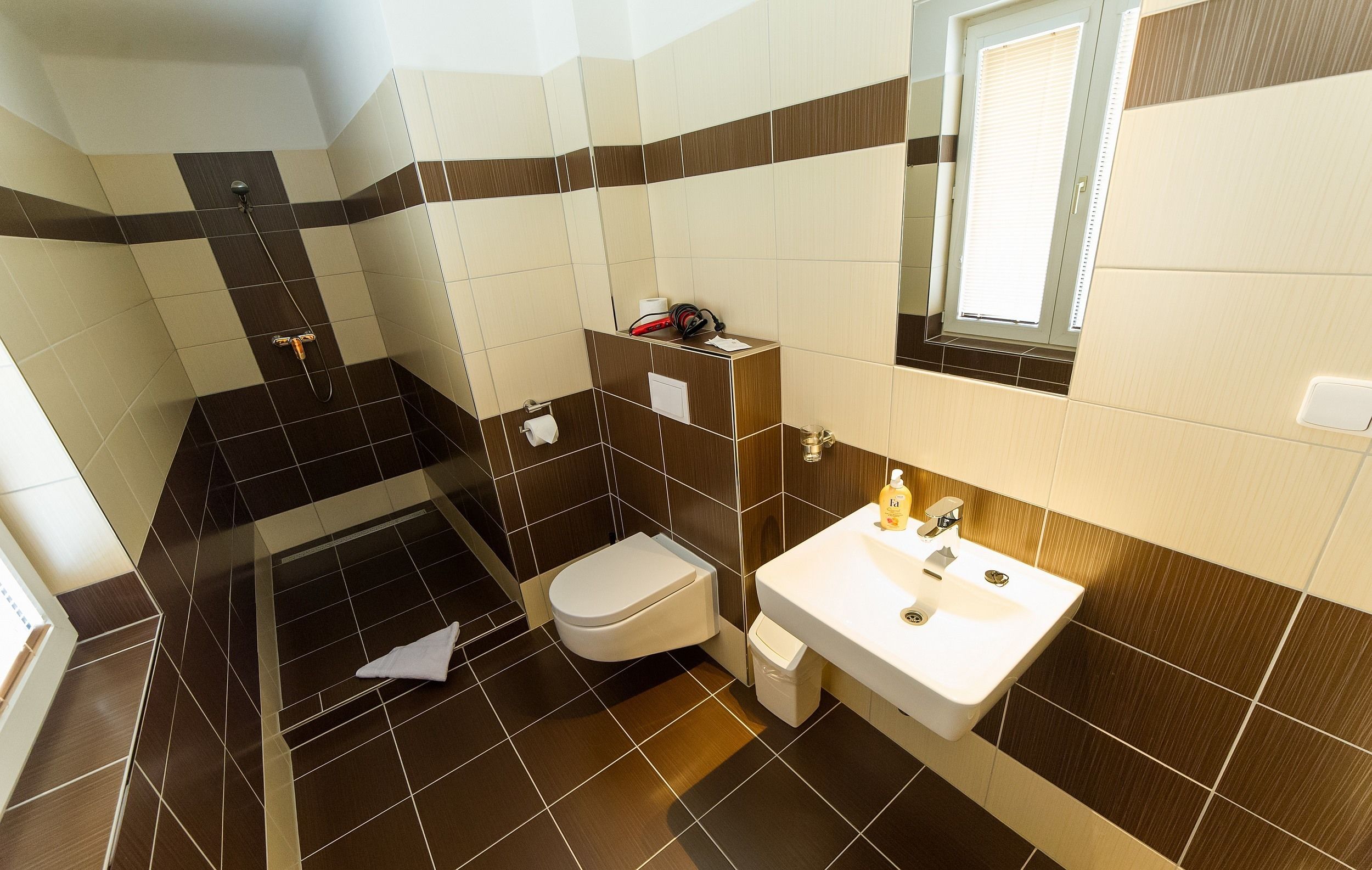 Un baño con ducha, inodoro, lavamanos y ventana.