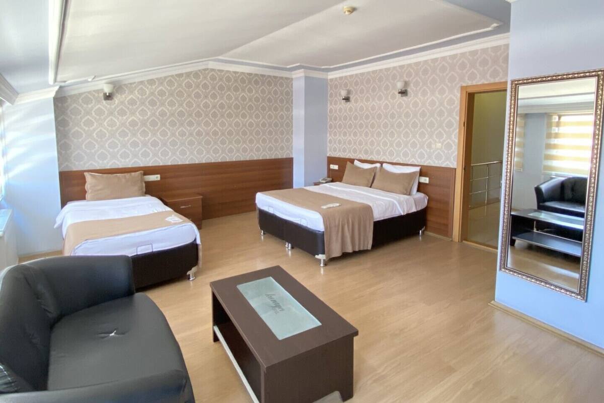 Ein Hotelzimmer mit zwei Betten, einem Schlafsofa, einem Couchtisch und einem großen Spiegel.