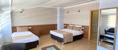 A hotel room with two beds, a sofa, a coffee table, and a large mirror.