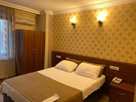 A hotel room with a bed, bedside table, and a telephone.