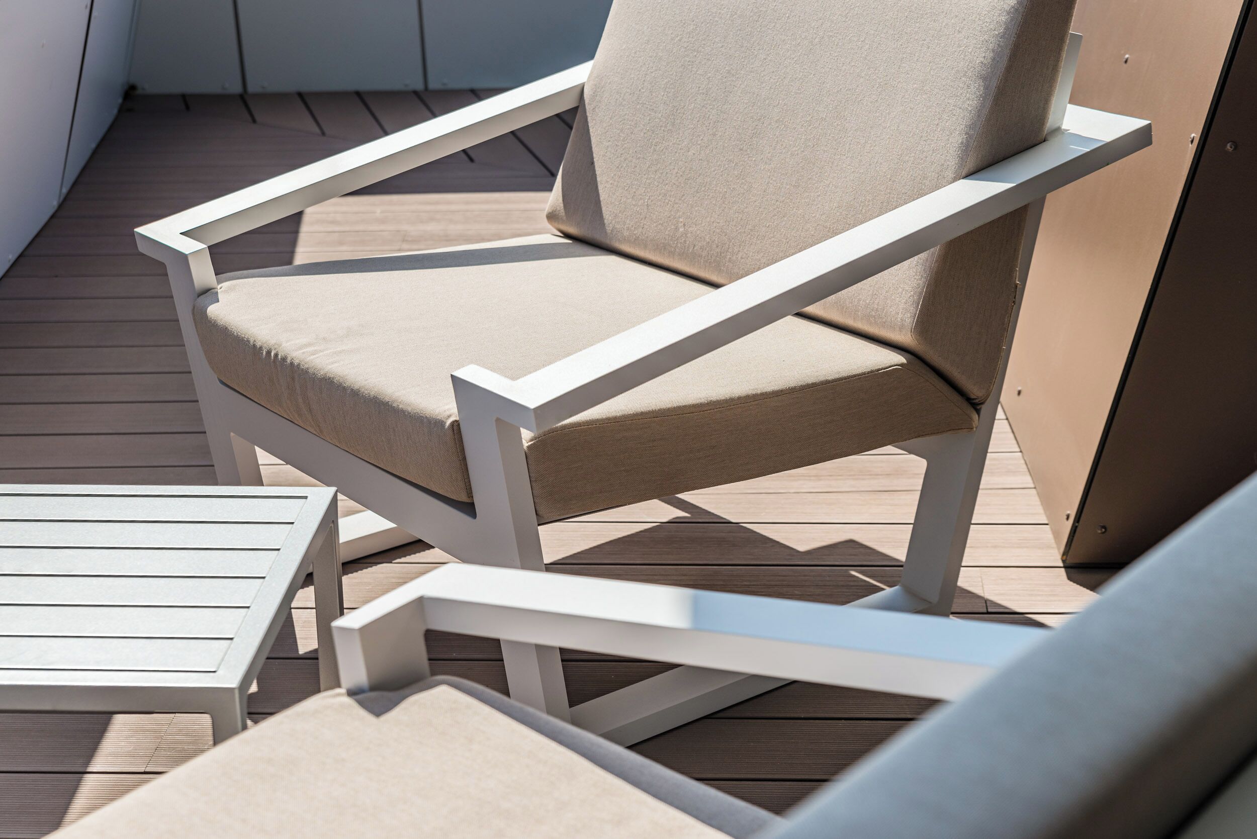 Una terraza con una silla blanca y una mesita.
