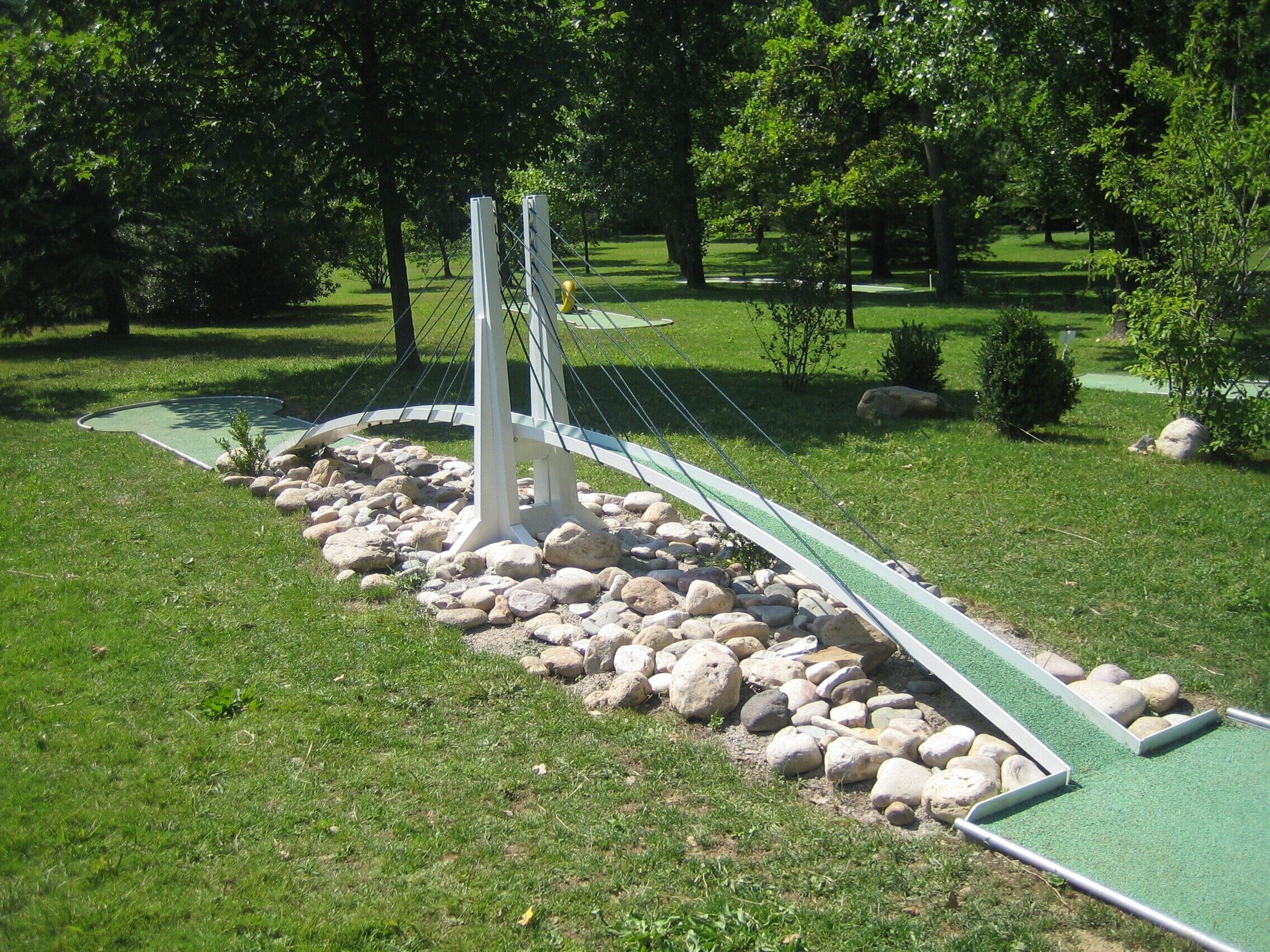 Ein grüner, künstlicher Golfplatz mit einer Brücke und Felsen.