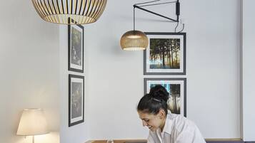 A modern dining area with a clean, minimalist design, featuring a table set for two with glasses and cutlery, and a person attending to the table.